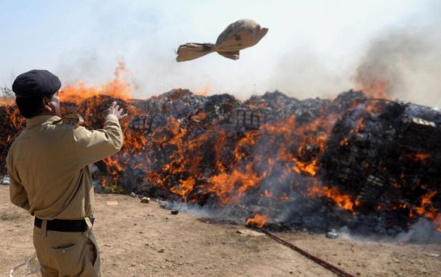 A Pakistani custom official throws a bag of narcotics onto fire at a ceremony in Karachi on January 26, 2014. Pakistani custom officials destroyed narcotics and other contraband items from different parts of the country to mark the occasion of International Customs Day. AFP PHOTO/Rizwan TABASSUM