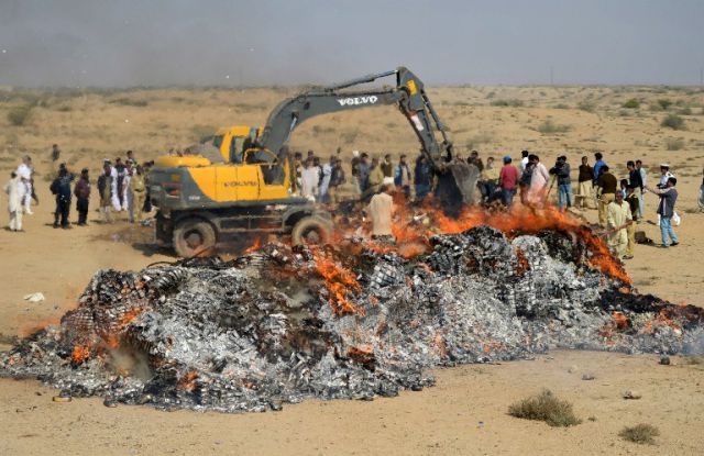 Pakistani custom officials burn seized liquor and drugs at a ceremony in Karachi on January 26, 2014. Pakistani custom officials destroyed narcotics and other contraband items from different parts of the country to mark the occasion of International Customs Day. AFP PHOTO/Rizwan TABASSUM