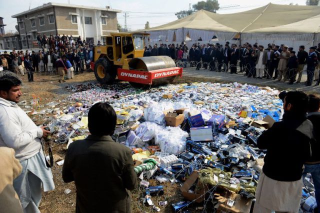 Pakistani customs officials use a steamroller to crush bottles of liquor at a ceremony in Islamabad on January 26, 2014. Pakistani custom officials destroyed narcotics and other contraband items different part of the country to mark the occasion of International Customs Day. AFP PHOTO/Farooq NAEEM