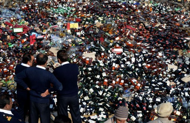 Pakistani customs officials look the bottles of liquor before destroying them at a ceremony in Lahore on January 26, 2014. Pakistani custom officials destroyed narcotics and other contraband items from different parts of the country to mark the occasion of International Customs Day. AFP PHOTO/Arif ALI