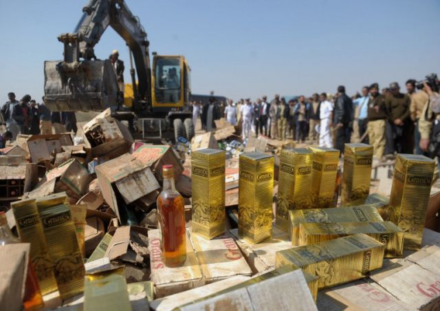 Pakistani custom officials prepare to destroy bottles of seized liquor at a ceremony in Karachi on January 26, 2014. Pakistani custom officials destroyed narcotics and other contraband items from different parts of the country to mark the occasion of International Customs Day. AFP PHOTO/Rizwan TABASSUM