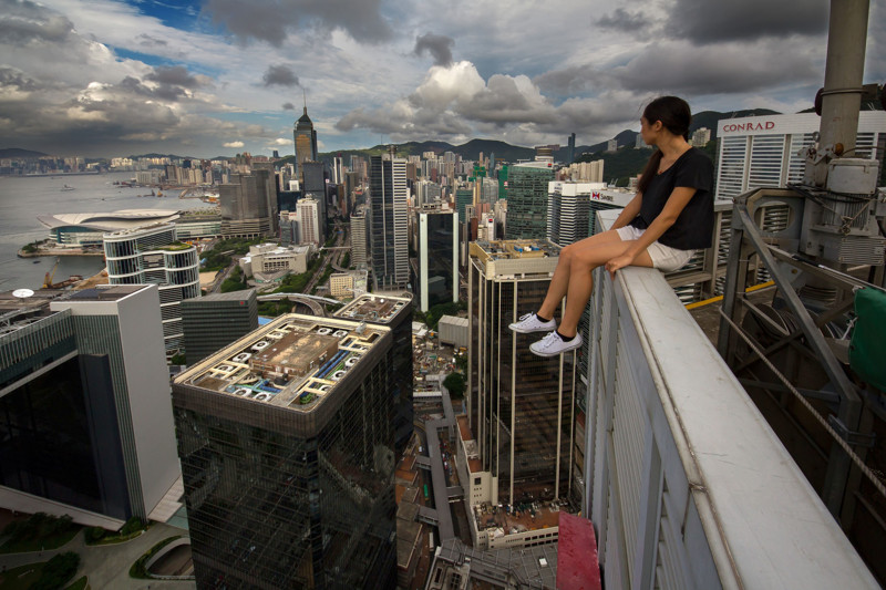 PIC BY ALEXANDER REMNOV / CATERS NEWS - (PICTURED One of the crazy climbers sits on the edge of a skyscraper in Hong Kong) These breath-taking images taken from the top of skyscrapers are wrong on so many levels. Captured using a specially adapted selfie stick, the sweat inducing images show the lengths some people will go to for the most extreme self portrait. Pictured at heights over 360 metres in the air, the nerve shredding photographs show the group of photographers dangling by one hand and even tip-toeing across tiny ledges. Seemingly unfazed by the dazzling heights, the barmy bunch ventured around the city of Hong Kong in search of any building that caught their eye. SEE CATERS COPY **NOT FOR SALE / USE IN RUSSIA / POLAND**