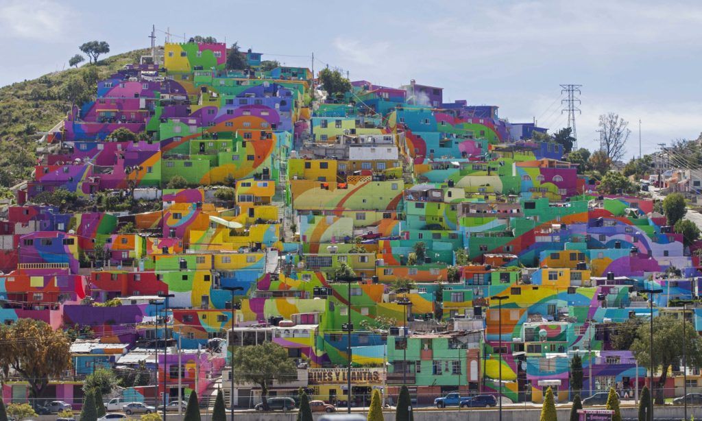 In this Thursday, July 30, 2015 photo, hundreds of houses painted in bright colors in what organizers claim is Mexico's largest mural, is part of a government-sponsored project is called Pachuca Paints Itself, in the Palmitas neighborhood, in Pachuca, Mexico. German Crew is the artist collective responsible for painting the mural project. Director Enrique Gomez, who goes by MYBE, said the crew has painted 1,500 square meters with 20,000 liters of paint. The project aims to bring the community together and rehabilitate the area. (AP Photo/Sofia Jaramillo)
