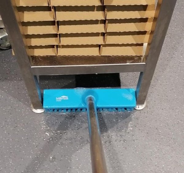 Modrá kefa vložená do medzery pod regálom
