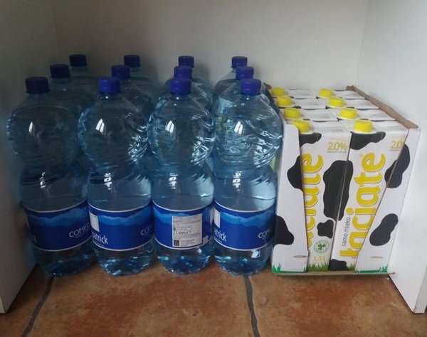 Veľké fľaše a nápojové kartóny tesne zoradené v rohu