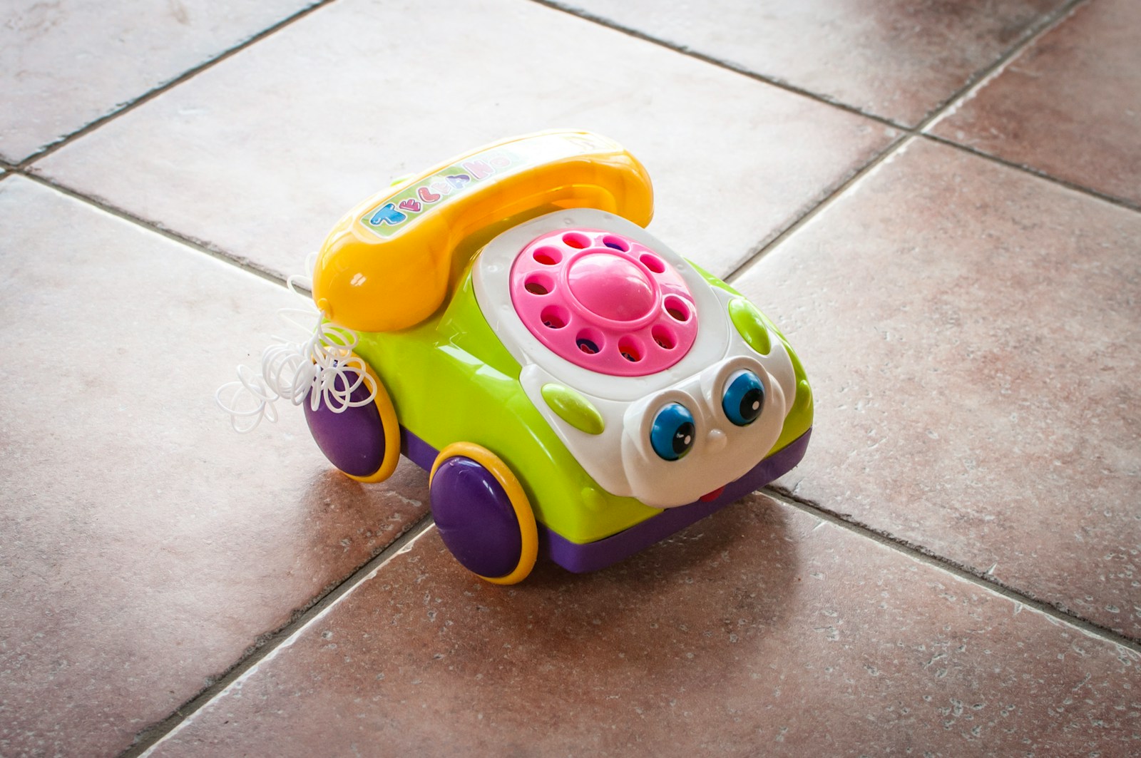 A toy car sitting on a tile floor