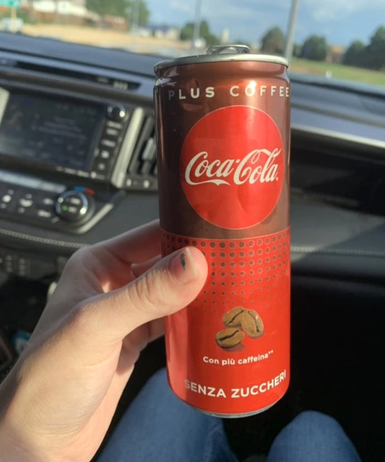 Červená plechovka nápoja s označením Plus Coffee držaná v ruke
