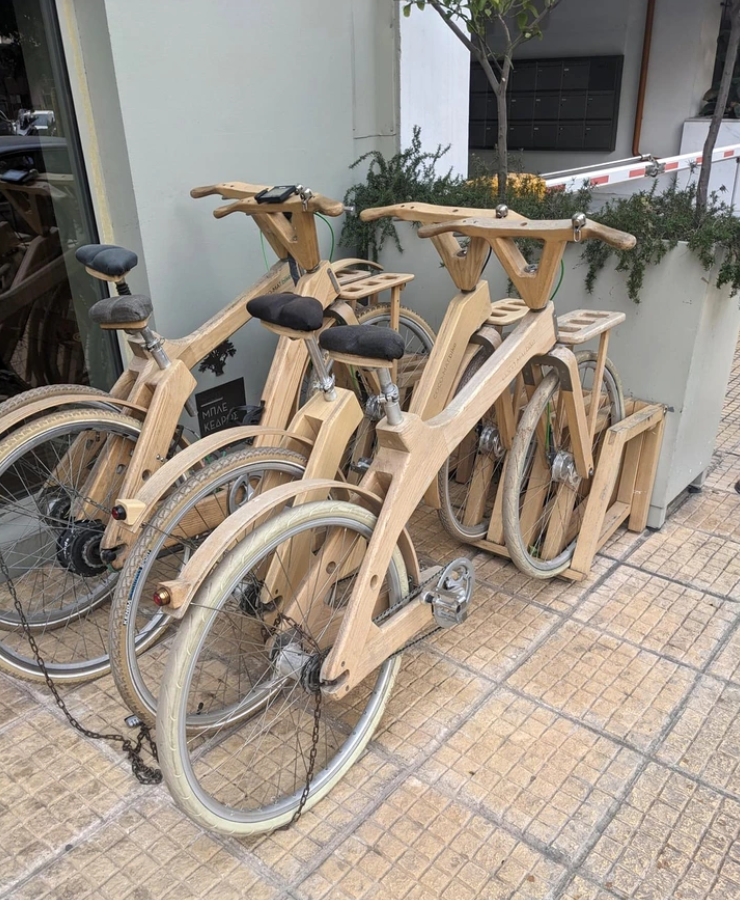 Niekoľko bicyklov so svetlými drevenými rámami a blatníkmi pred budovou