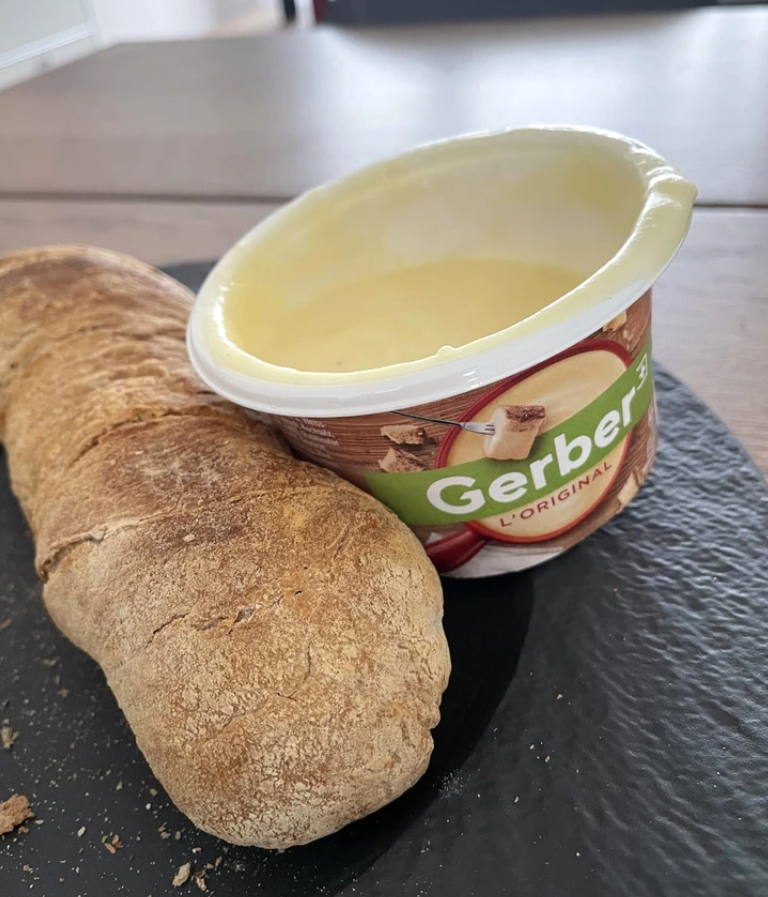 Otvorený pohárik so syrovou zmesou vedľa kusu pečiva