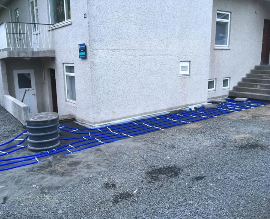 Modré rúrky uložené pri dome pred zakrytím povrchom