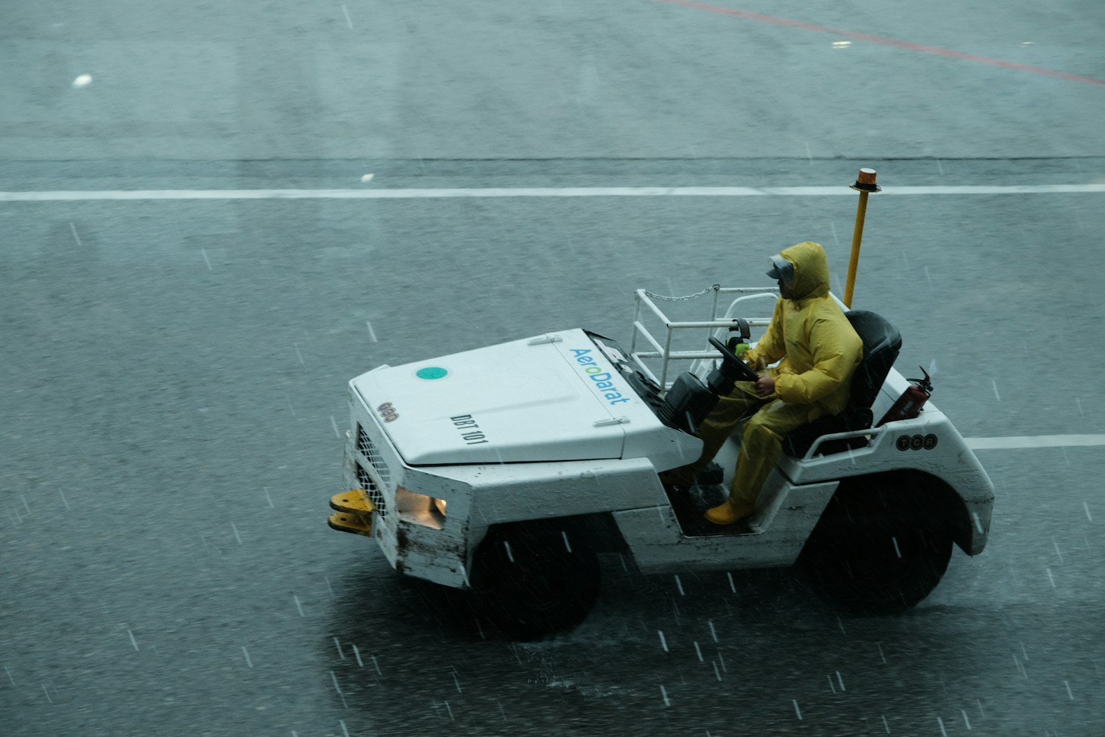 A man in a yellow rain suit driving a white vehicle