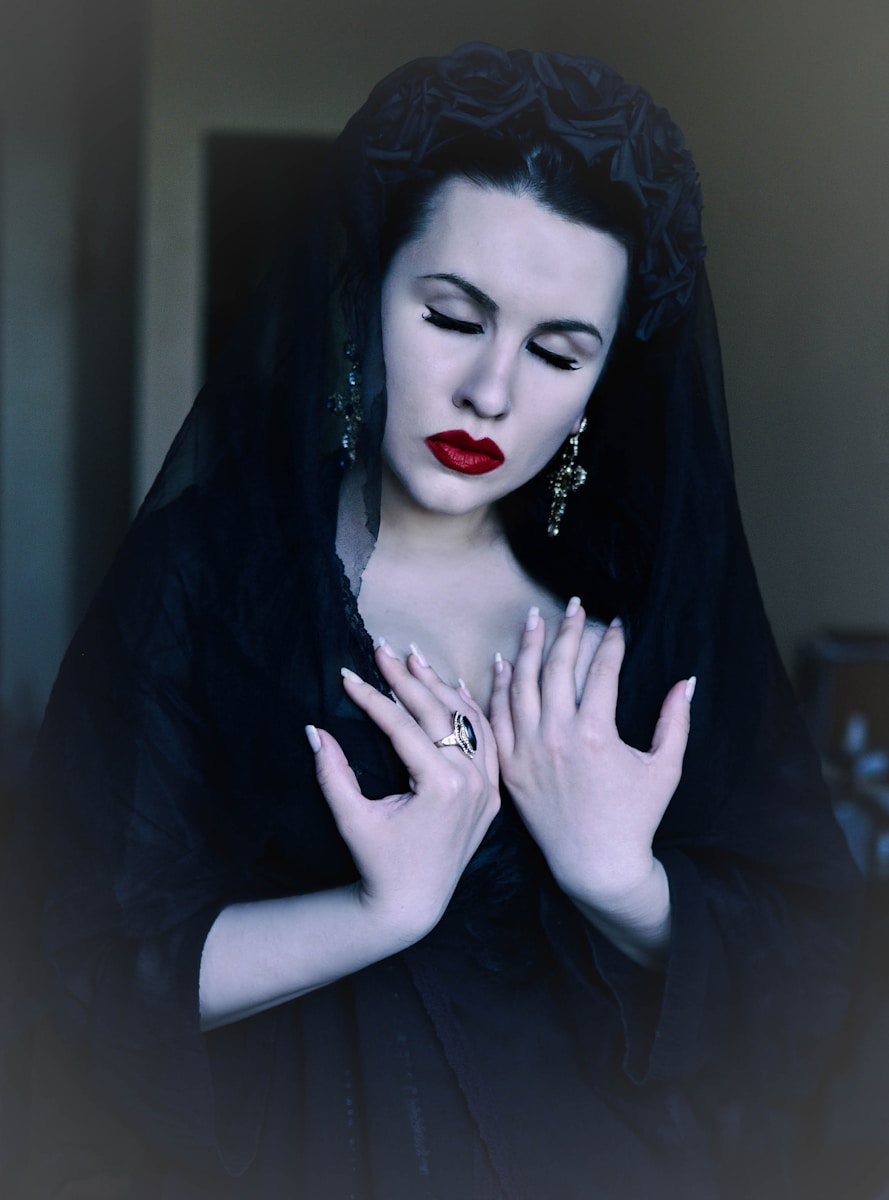 a woman wearing a black veil and holding her hands together