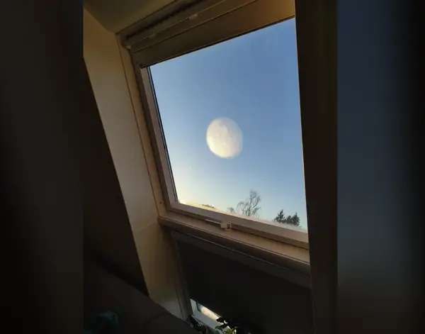 Svetlý kruh na skle pripomína nebeské teleso v modrom pozadí.