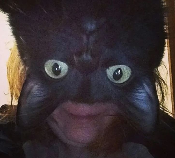 Tmavá zvieracia tvár splýva s vlasmi osoby za ňou.