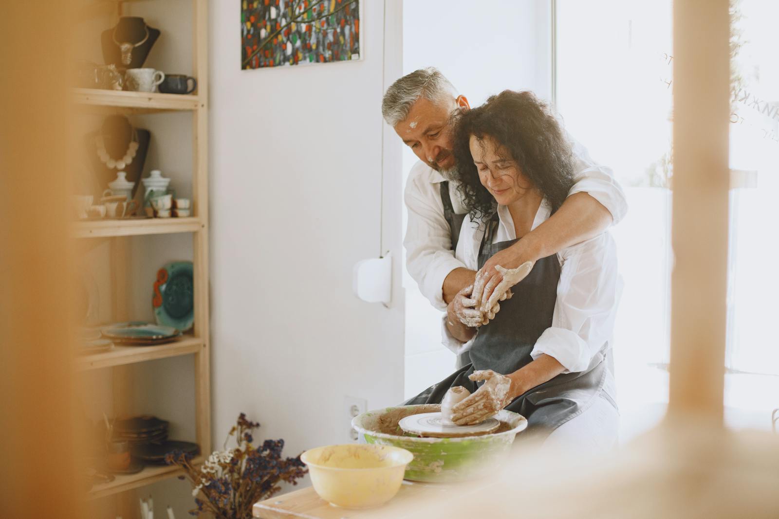 A loving couple enjoying pottery making together indoors, creating art on a wheel.