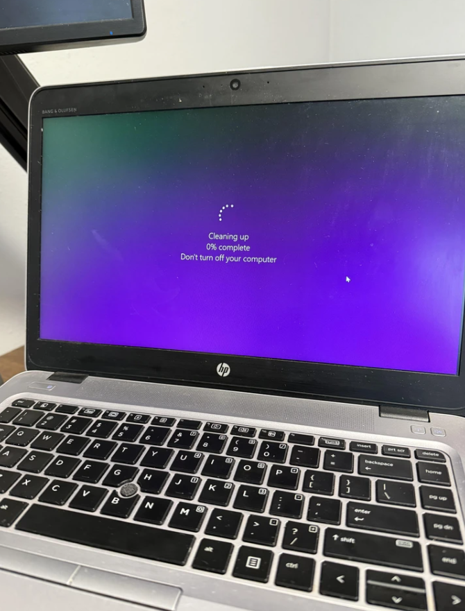 Notebook s hlásením Cleaning up, nulou percent a upozornením nevypínať počítač