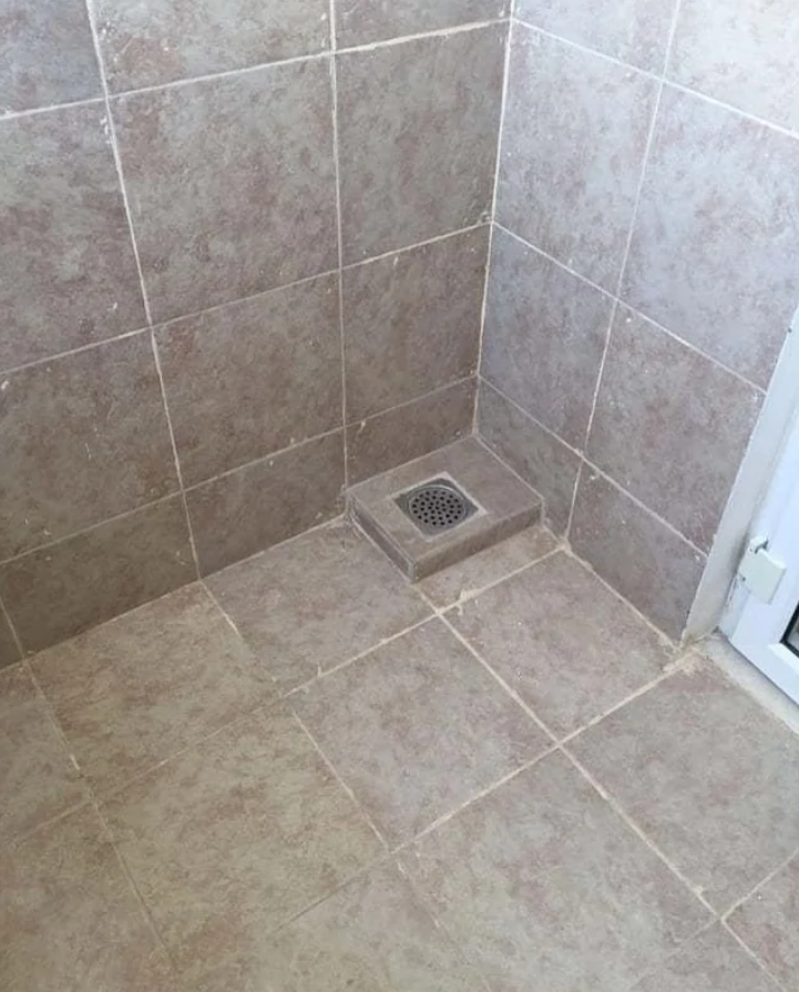 Odtoková mriežka je na vyvýšenom vydláždenom štvorci v rohu pri podlahe.