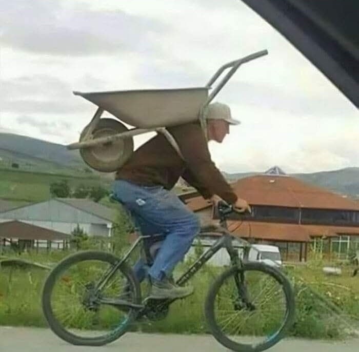 Cyklista má na chrbte fúrik, ktorého rúčky a koleso vyčnievajú nad telo.
