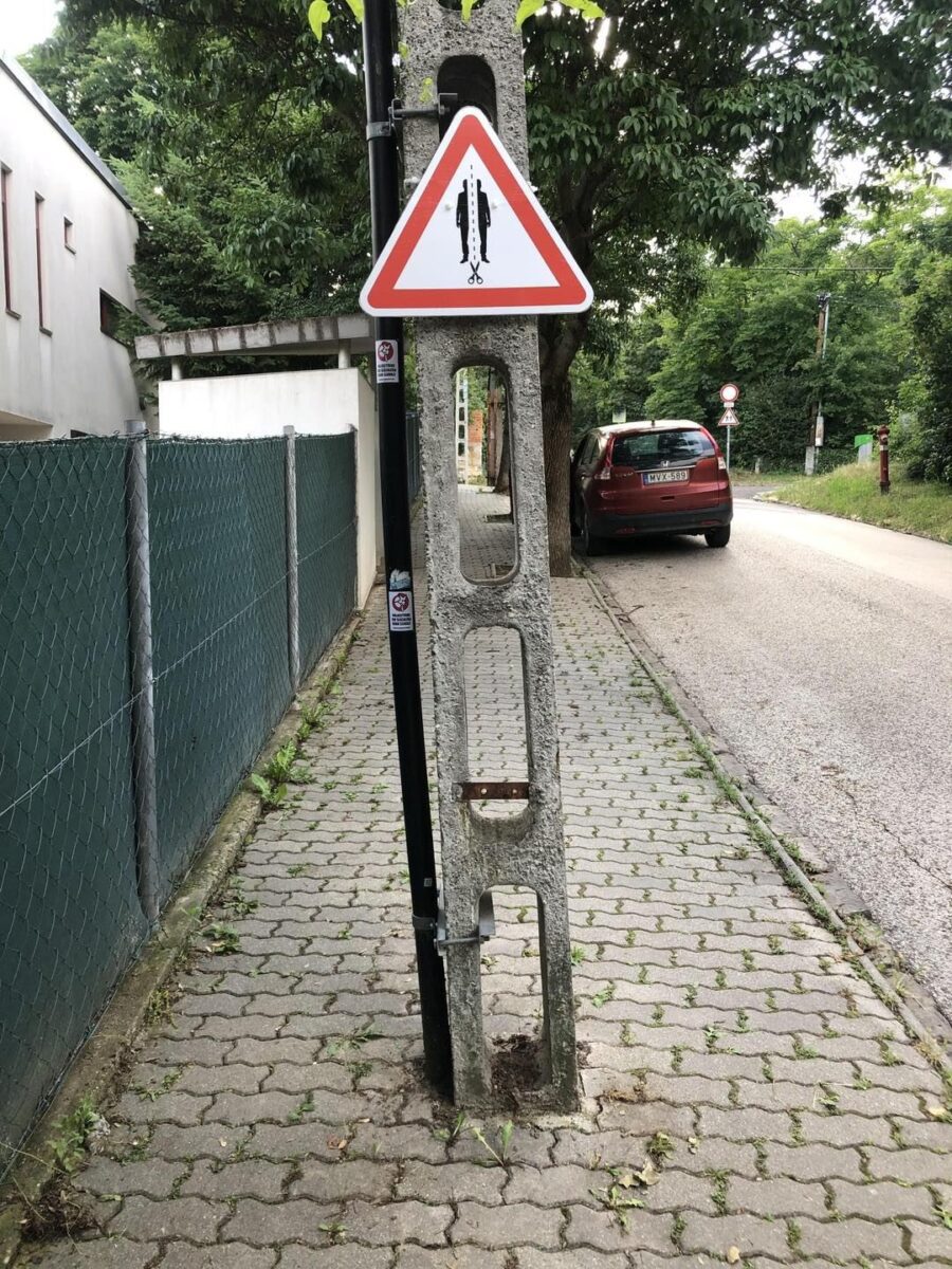 Dopravná značka nad úzkym betónovým stĺpom pri chodníku
