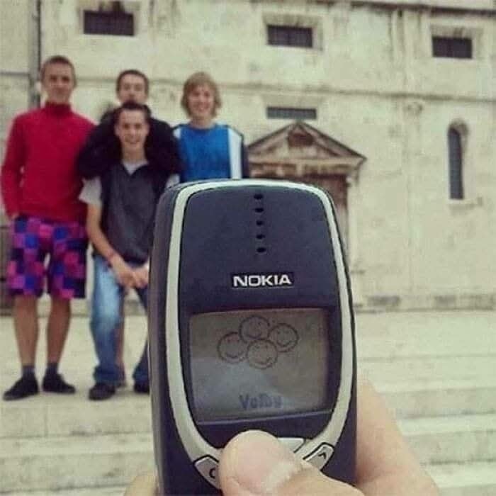 Starší telefón Nokia držaný v popredí pred skupinou ľudí.