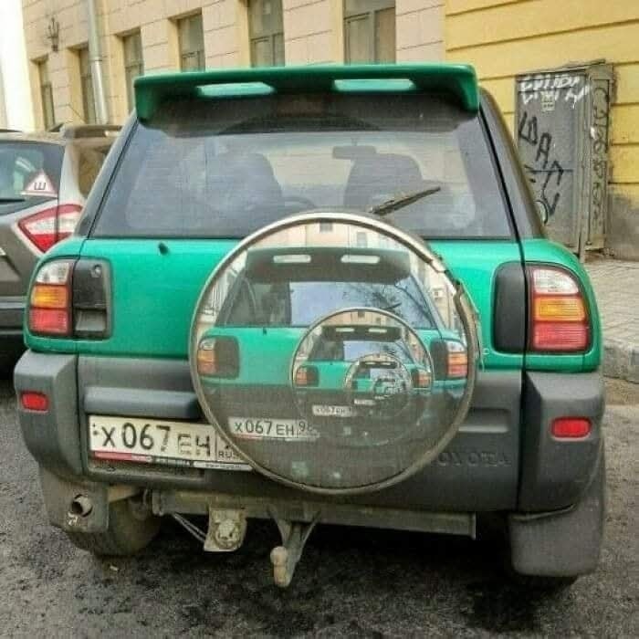 Zelené auto má na kryte rezervného kolesa fotografiu svojej zadnej časti.