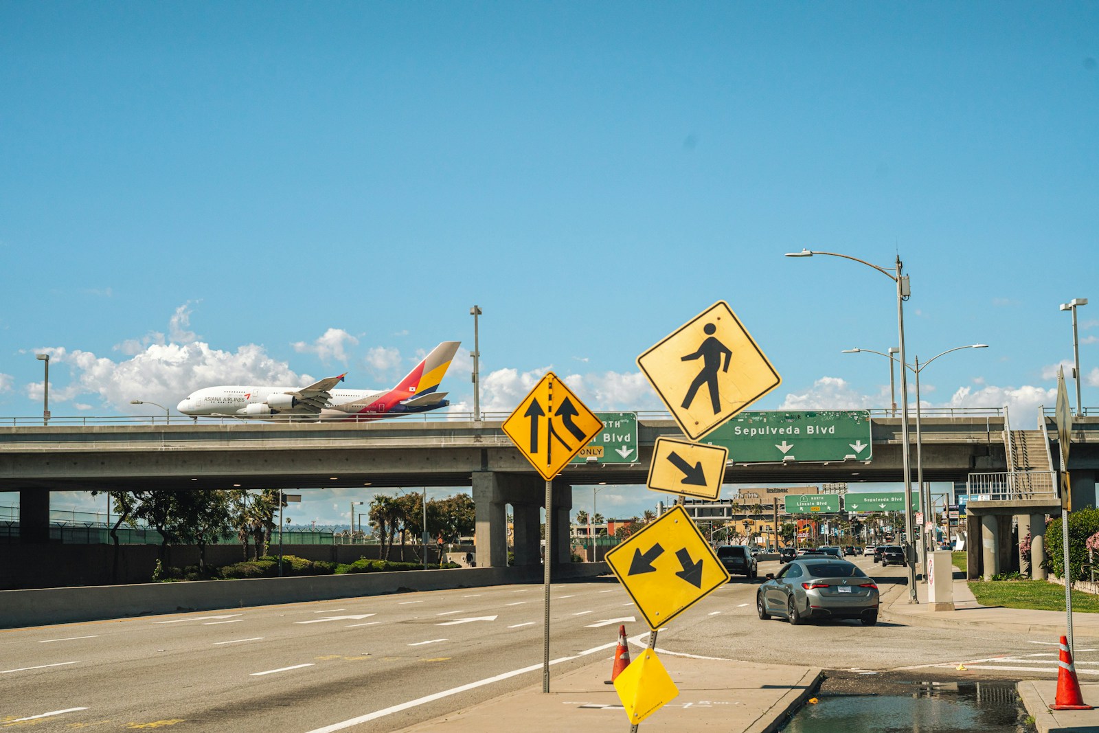 a plane is flying over a highway with traffic signs