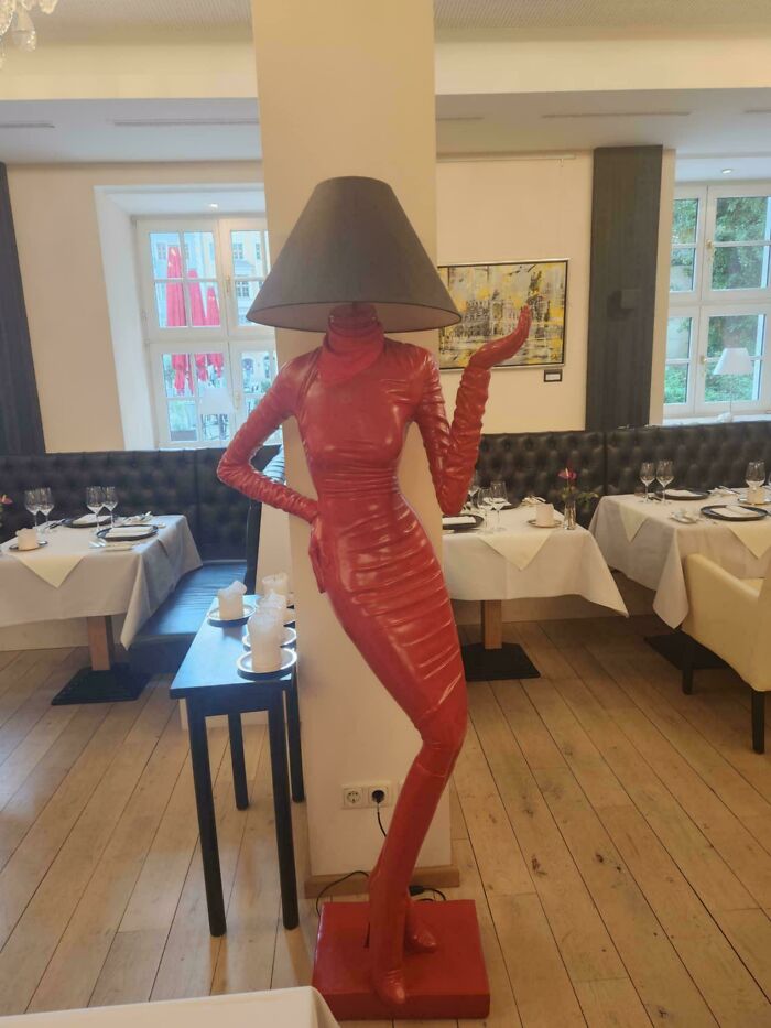 Lampa v tvare postavy v červenom šate v reštaurácii, kreatívny dizajn osvetlenia.