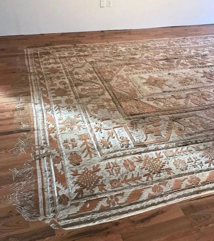 Koberec so zložitým vzorom na drevenej podlahe, kombinácia tradičných ornamentov a prírodných farieb.