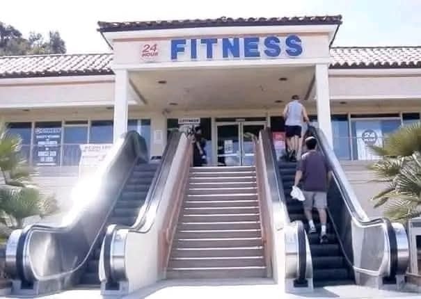 Ľudia stúpajú po eskalátoroch k 24-hodinovému fitness centru.
