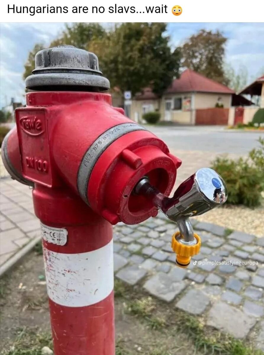 Červený hydrant s nezvyčajným kovovým prvkom na vývode.