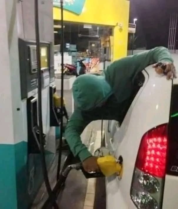Osoba v mikine tankuje auto na benzínovej pumpe za zvláštnych podmienok.