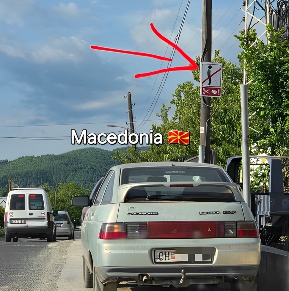 Dopravná značka pri ceste so samolepkou a červenou šípkou v obrázku.