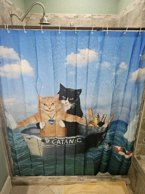 Sprchový záves s mačkami na lodi Catánic, parodujúcimi scénu z Titanicu.