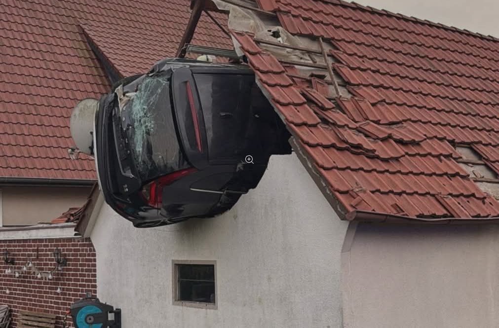 Automobil medzi červenými škridlami na streche domu.