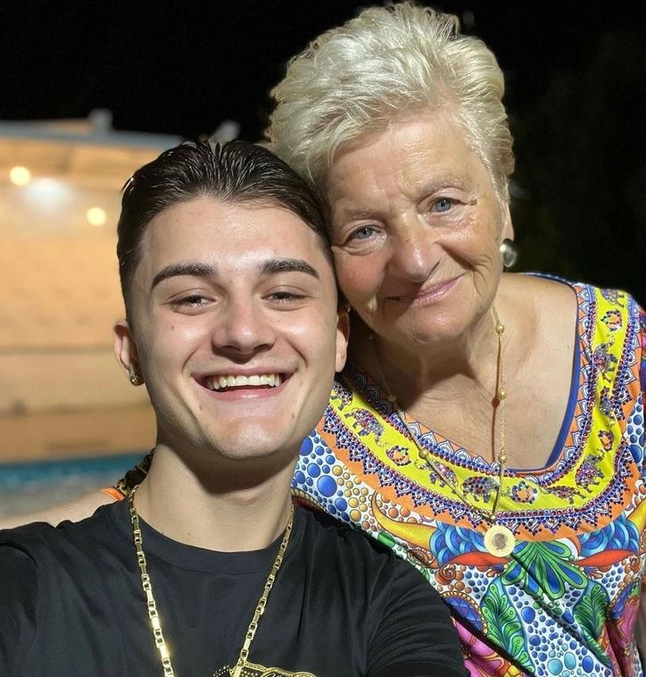 Osoby sa usmievajú, večerné selfie pri bazéne s pestrofarebnými šatami ženy. Harmonická rodinná chvíľa.