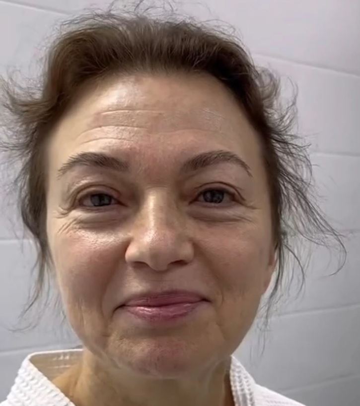 Usmievajúca sa žena s prirodzeným vzhľadom na svetlom pozadí.