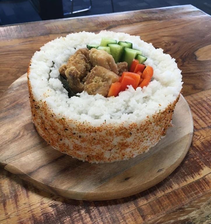 Obrovské sushi s ryžou, zeleninou, kuraťom a korením na drevenej doske. Ideálne pre milovníkov japonskej kuchyne.
