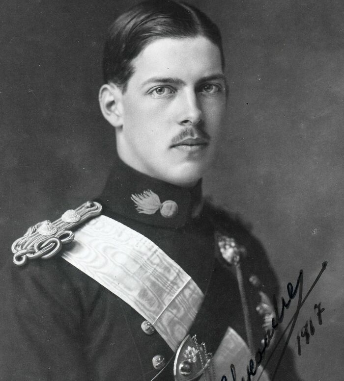 Oblečený muž v historickej uniforme s vyznamenaniami, čiernobiela fotografia z roku 1917.