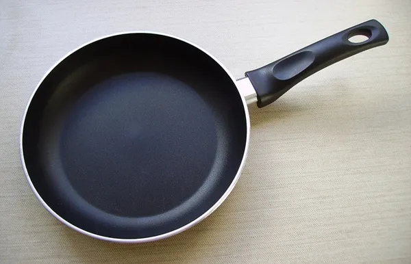 Čierna panvica s nepriľnavým povrchom a ergonomickou rukoväťou na svetlom pozadí.