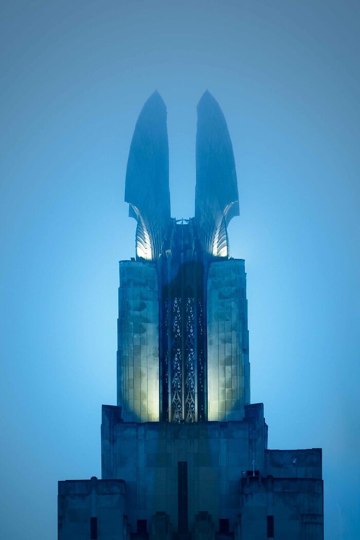 Osvetlená moderná veža v hmle, architektonický skvost na modrom pozadí.