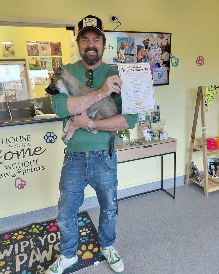 Muž s certifikátom adopcie a šteňaťom v útulku, úspešná adopcia domáceho maznáčika.