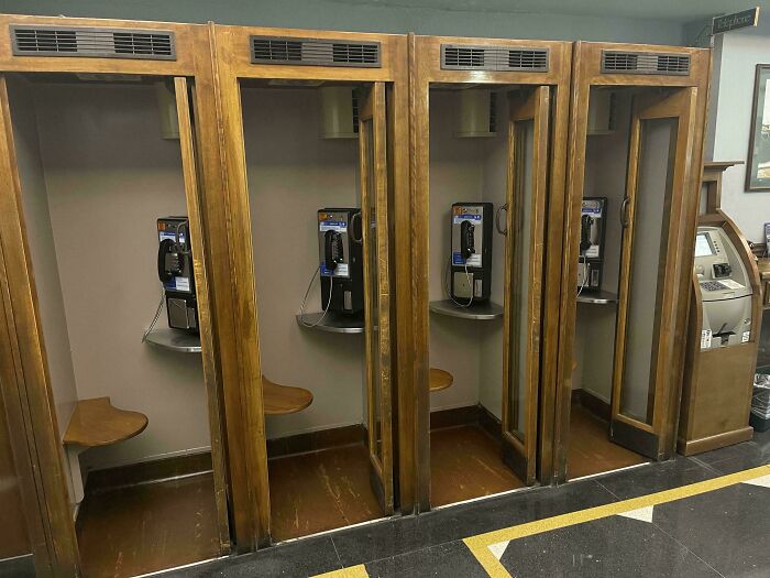 Retro telefónne búdky s verejnými telefónmi v historickom drevenom dizajne.