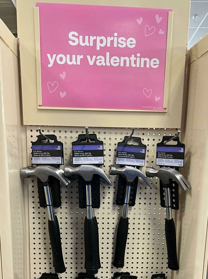 Kladivá na predaj s nápisom Prekvapte svoju valentínku, Valentínska výzdoba v obchode so železiarskym tovarom.