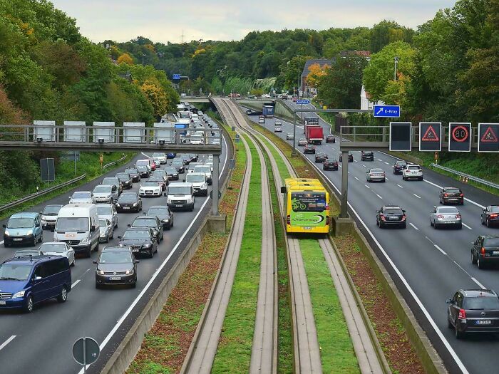 Dvojprúdová diaľnica s premávkou a samostatnou traťou pre autobusy uprostred zelene.