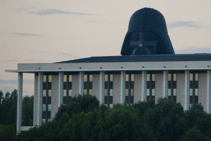 Budova s veľkou prilbou postavy z populárneho sci-fi filmu, obklopená stromami.