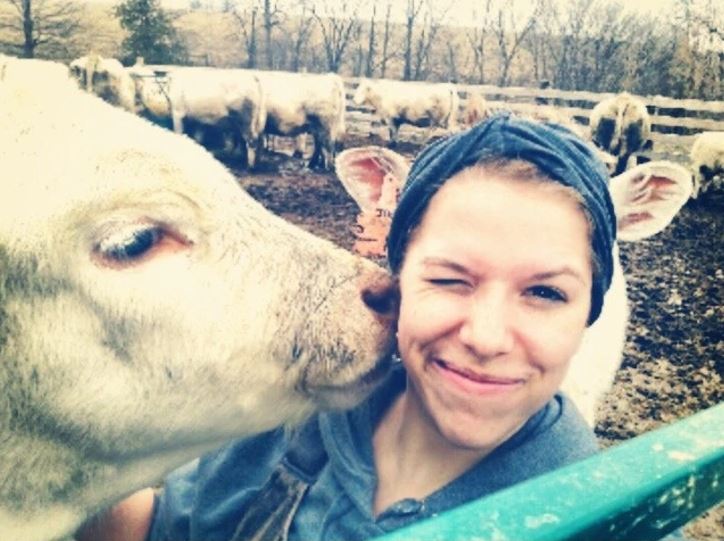 Osoba si robí selfie so zvedavým teľaťom na farme; usmievajúce sa, priateľské stretnutie.
