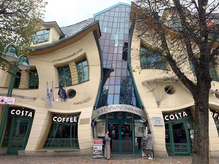 Krivý dom v Sopote, známa atrakcia s unikátnou architektúrou, kaviareň Costa v popredí.