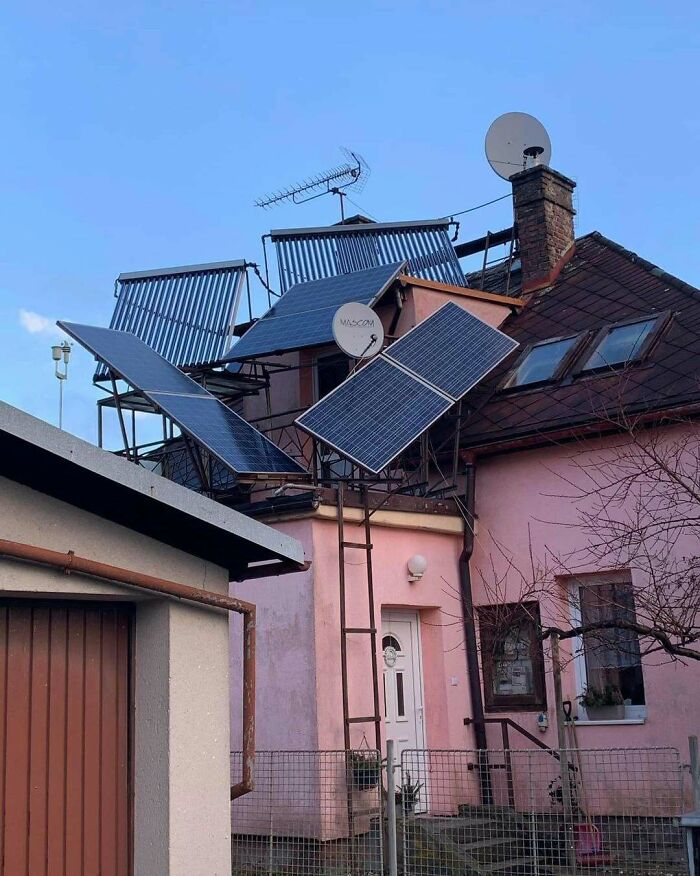 Rodinný dom so slnečnými kolektormi a satelitnými anténami na streche pod modrou oblohou.