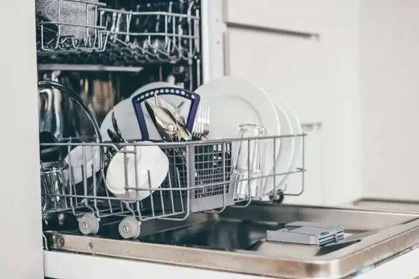 Umývačka riadu s čistým tanierom, príborom a pohármi, pripravené na vybratie a použitie.