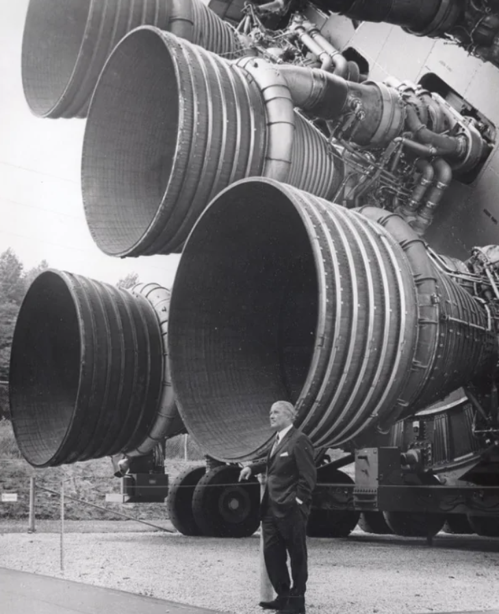 Obrovské raketové motory Saturn V s človekom stojacim vedľa na ilustráciu ich veľkosti.